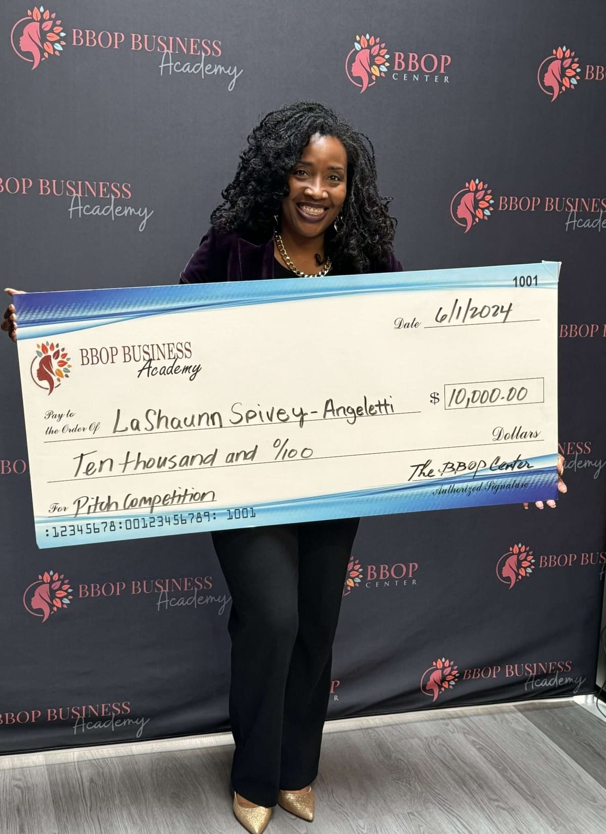 A BBOP Business Academy pitch winner holding a ten-thousand-dollar award check