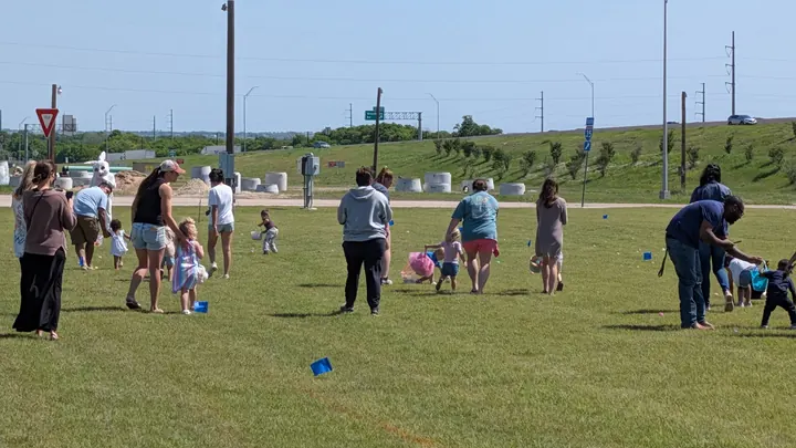 Parents and children spread across a wide green field at the City's Easter egg hunt.
