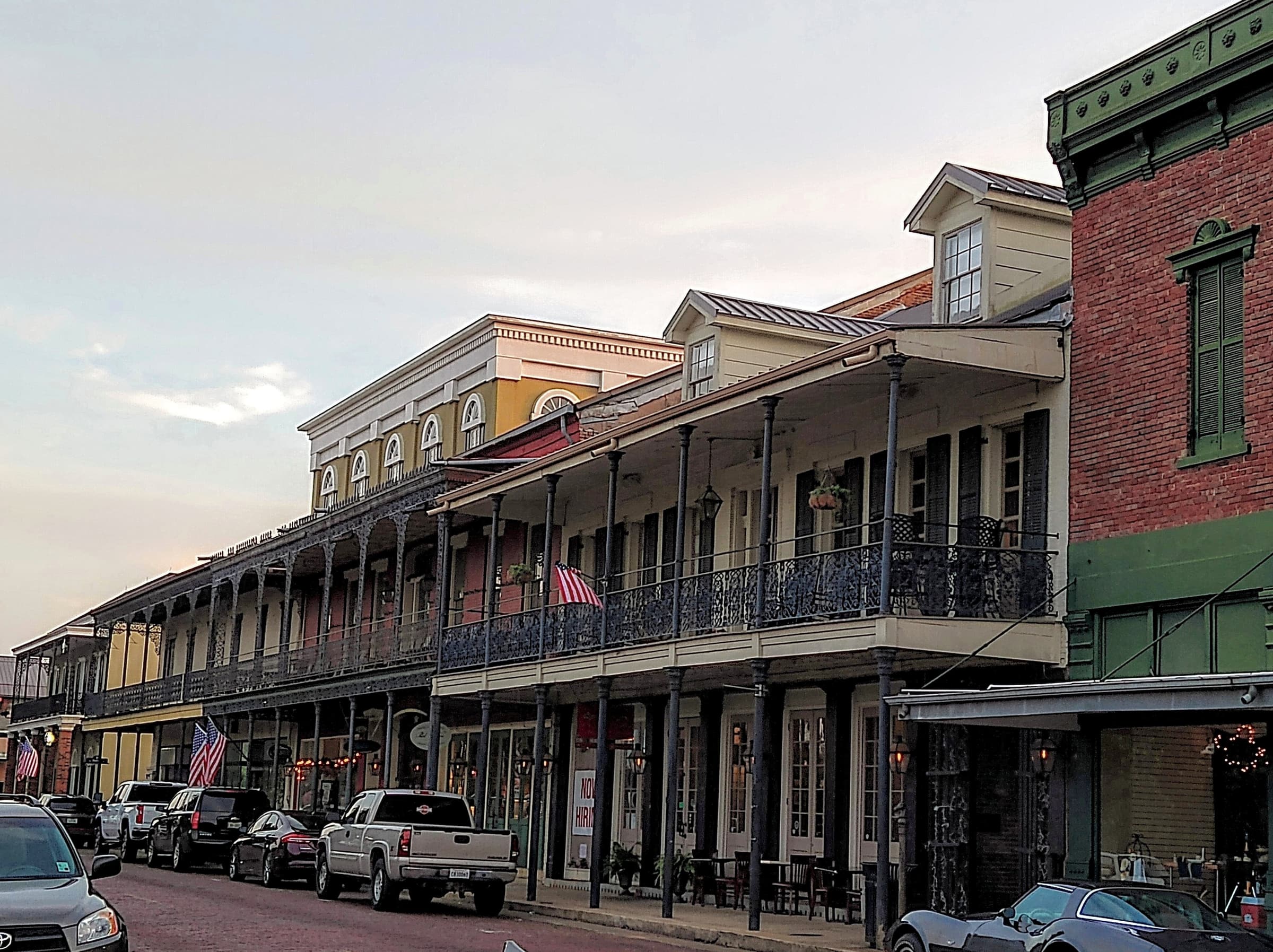 Iron-lace galleries and brick storefronts along a historic downtown street in Natchitoches, Louisiana.