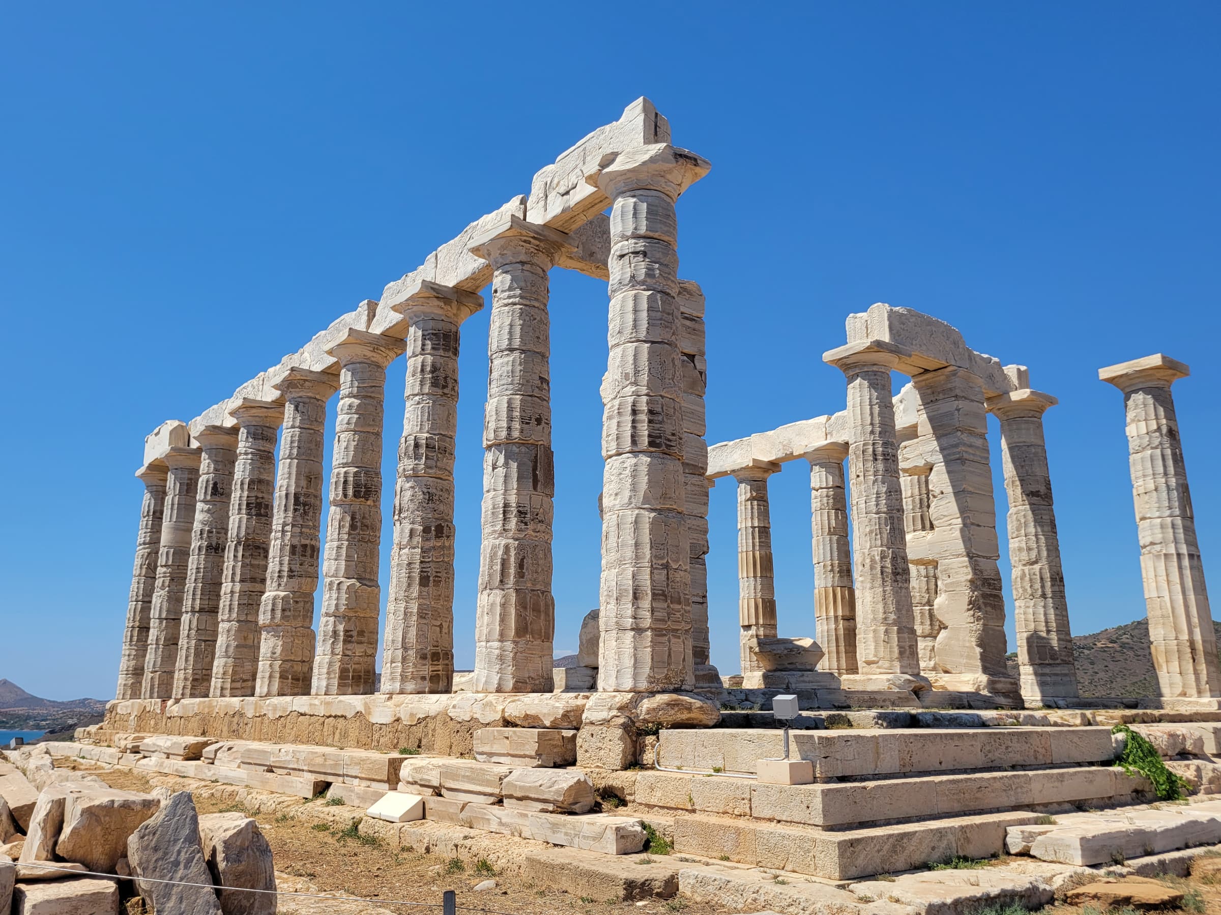 White marble columns of the Temple of Poseidon against the blue sky at Cape Sounion
