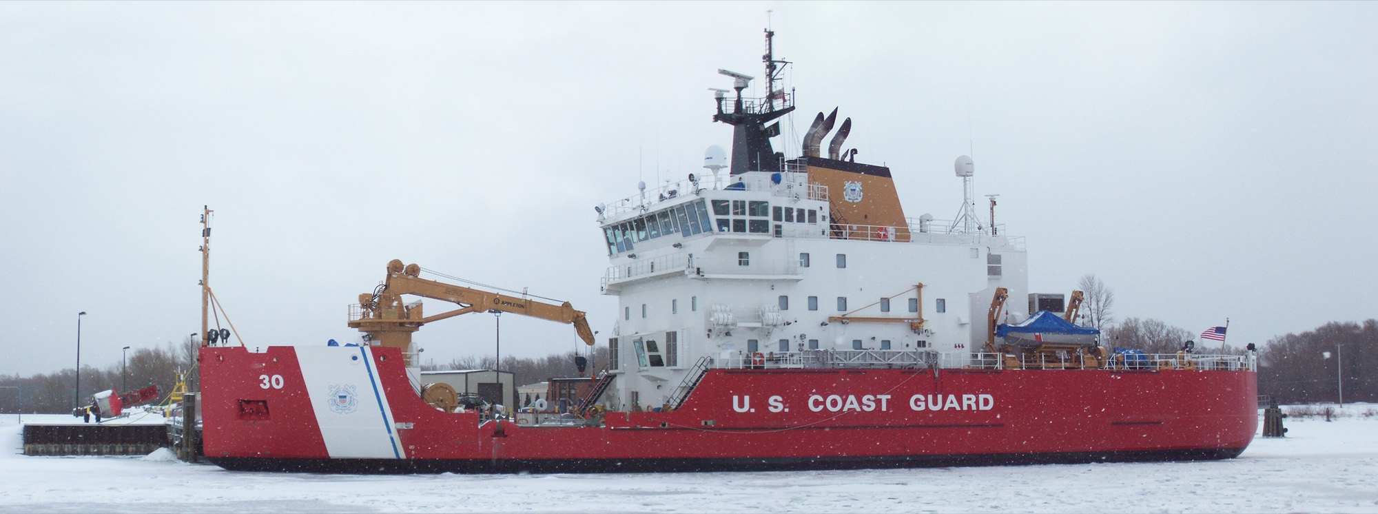 The US Coast Guard cutter Mackinaw, a 240-foot icebreaker with a red hull, underway on calm water.