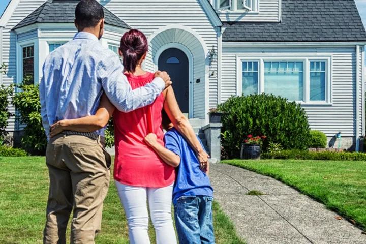 A family standing together on the lawn in front of a grey clapboard Connecticut house.