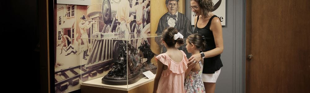 A mother and two daughters looking at an exhibit case in the museum.