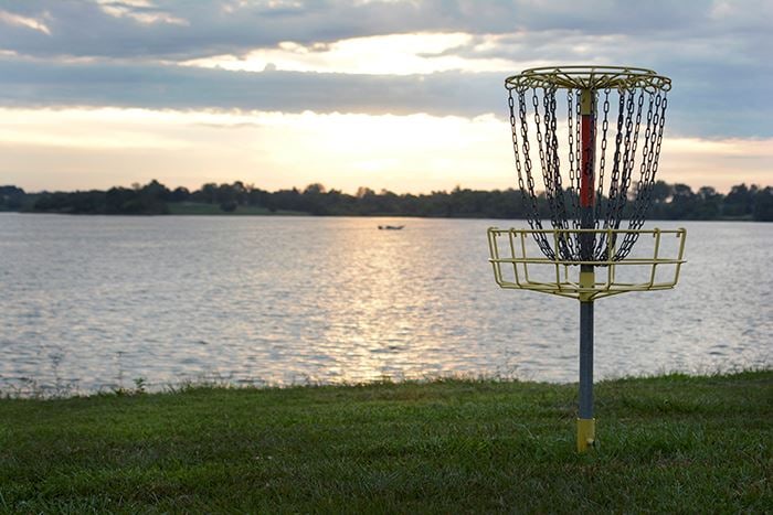 A disc golf basket above the lake at sunset.