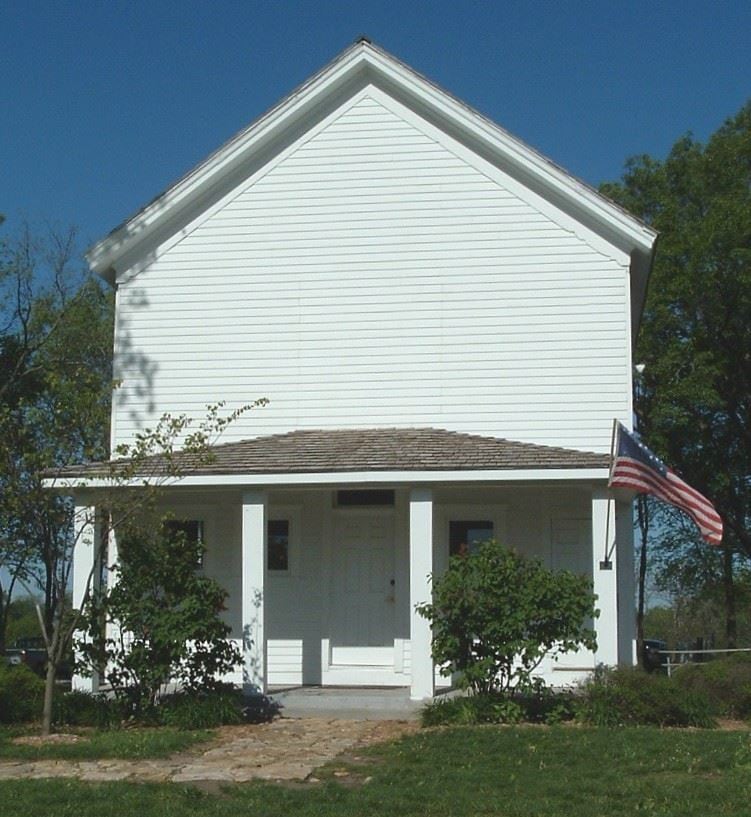 The white frame Mt. Gilead one-room schoolhouse with a flag by the door.