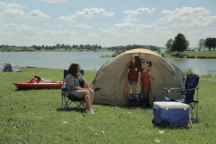 A family camping in a dome tent on the grass by Smithville Lake.
