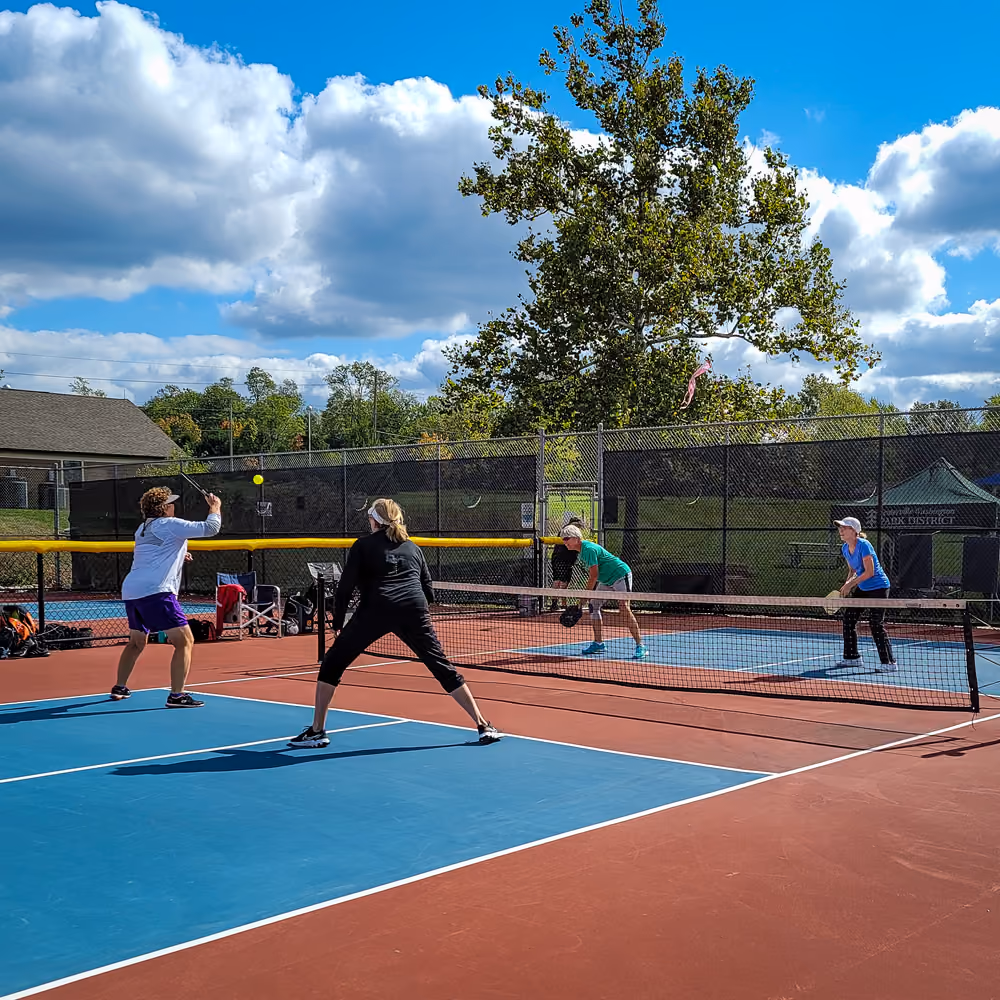 Four players mid-rally on the pickleball courts