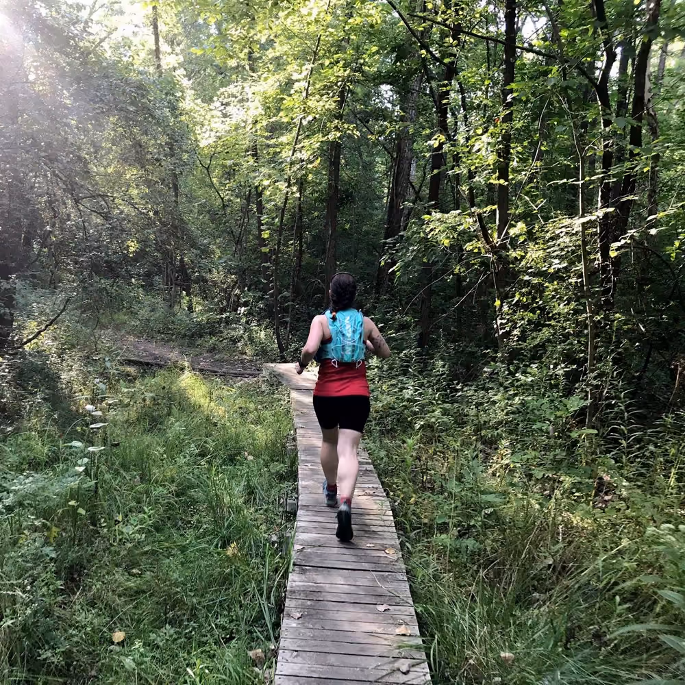 A runner on the boardwalk trail through the woods at Bill Yeck Park