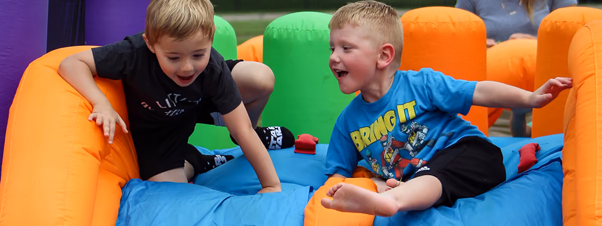 Two boys racing down an inflatable slide at the Big Backyard Party