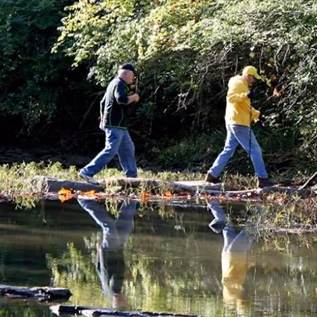 Two hikers crossing Holes Creek on stepping stones at Grant Park