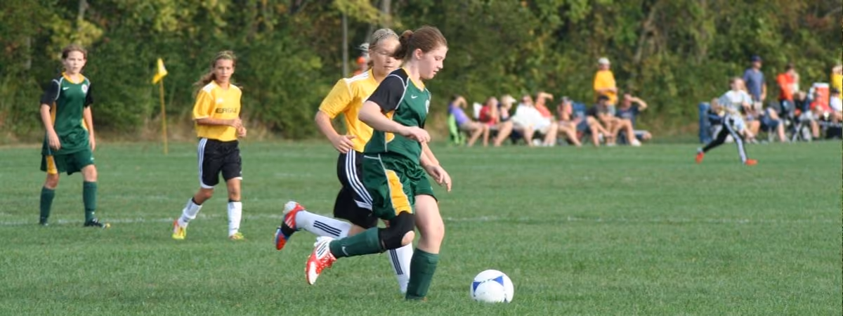 Young soccer players chasing the ball on an Oak Grove Park field