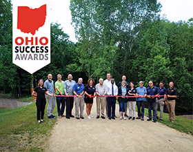 Ohio Success Award banner over an image of people standing across a limestone path cutting a red ribbon