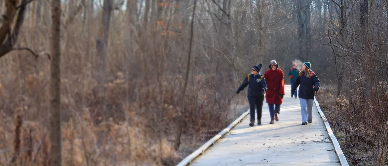 Four people walking a boardwalk at Bill Yeck Park in winter