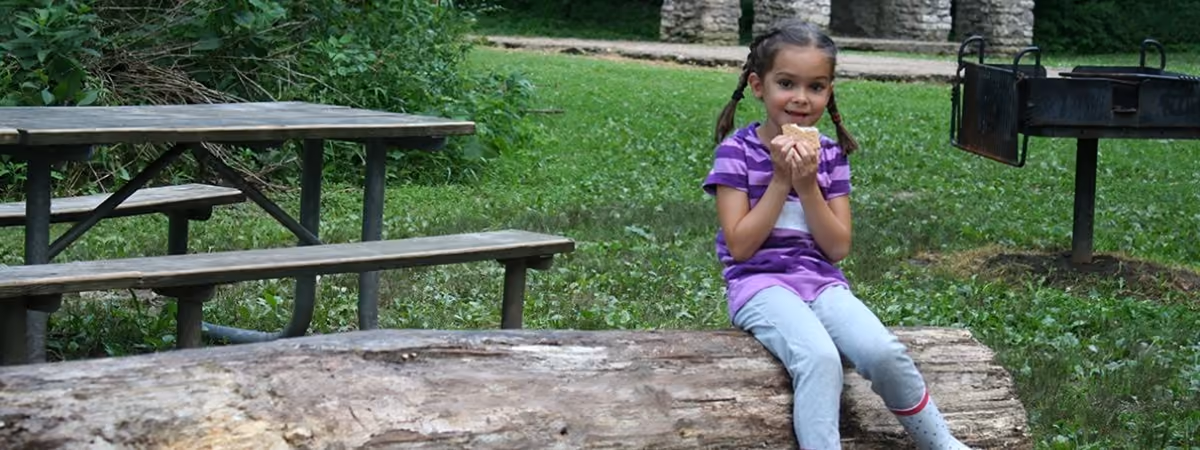 A girl sitting on a log bench at the Grant Park fire circle