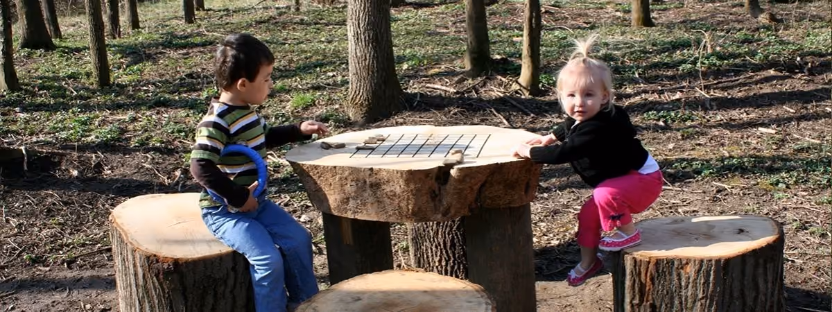 Two children at a log table in the natural play area at Grant Park
