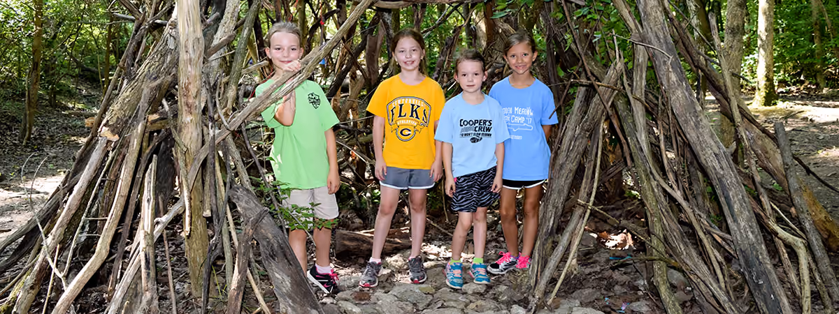Campers standing in a stick fort they built at summer camp