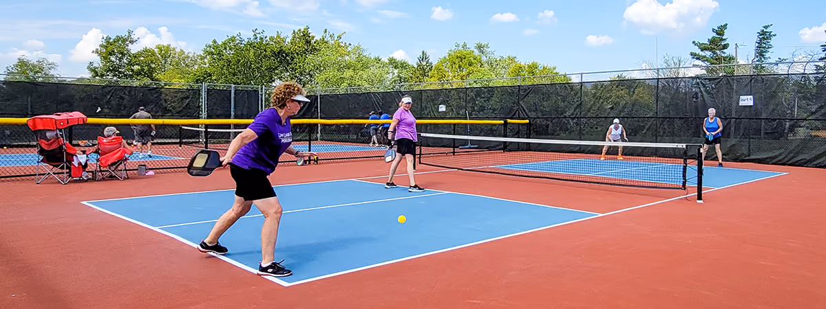 Pickleball players on blue and red courts