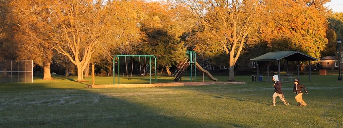 Evening light on the trees, swings and shelter at Village South Park