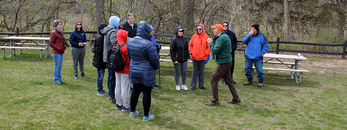 Adults in winter coats gathered on a park lawn for a volunteer-led program