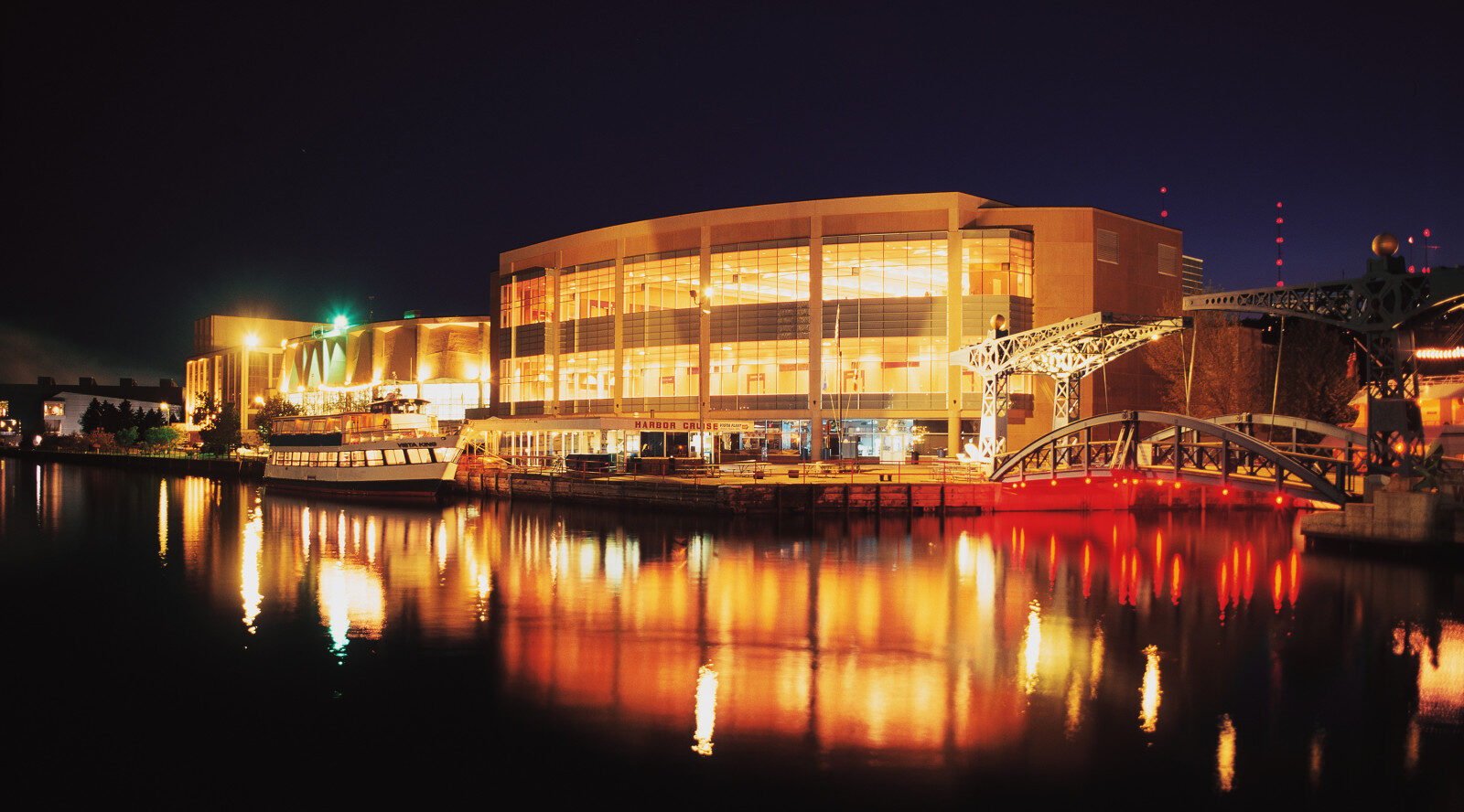 The DECC complex glowing at night, reflected in the dark water of the Duluth harbor