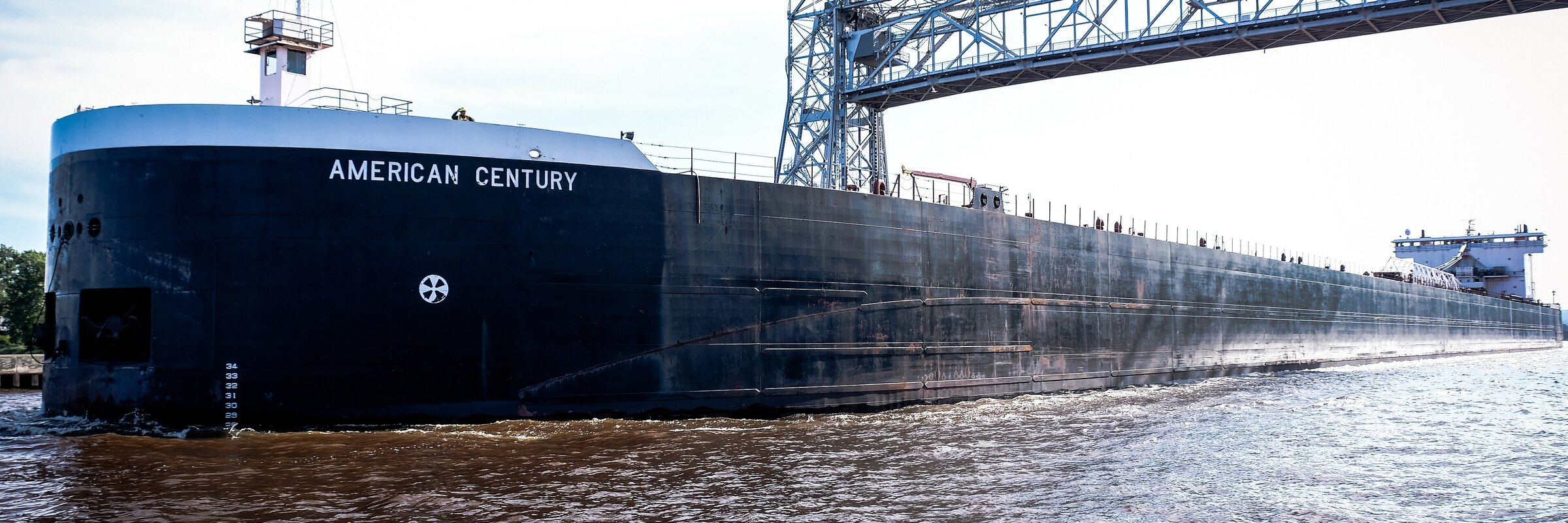 A Great Lakes freighter passing Duluth's Canal Park, the Aerial Lift Bridge rising behind it