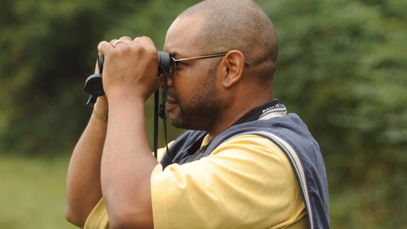 A birder with binoculars raised