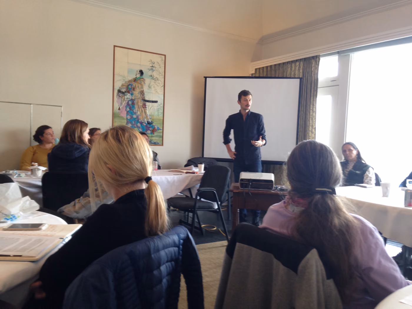 A presenter speaking to round tables of attendees at an ADI gathering