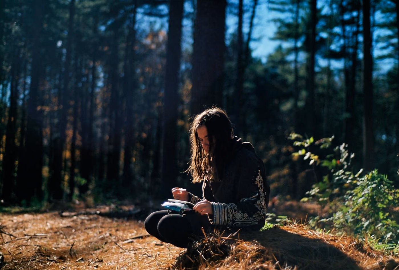 Writing in a journal on the forest floor