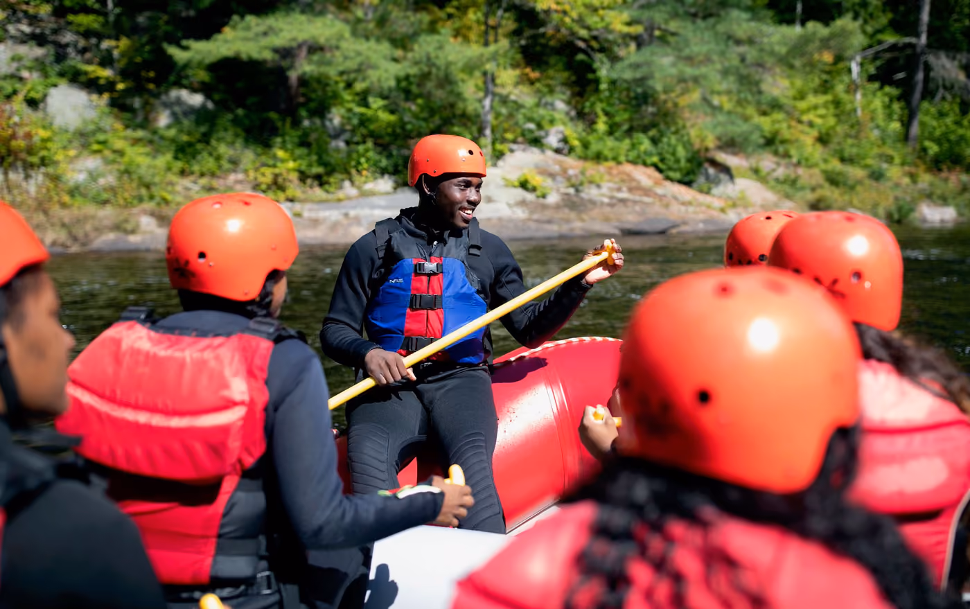 Rafters in red helmets paddling hard through a rapid