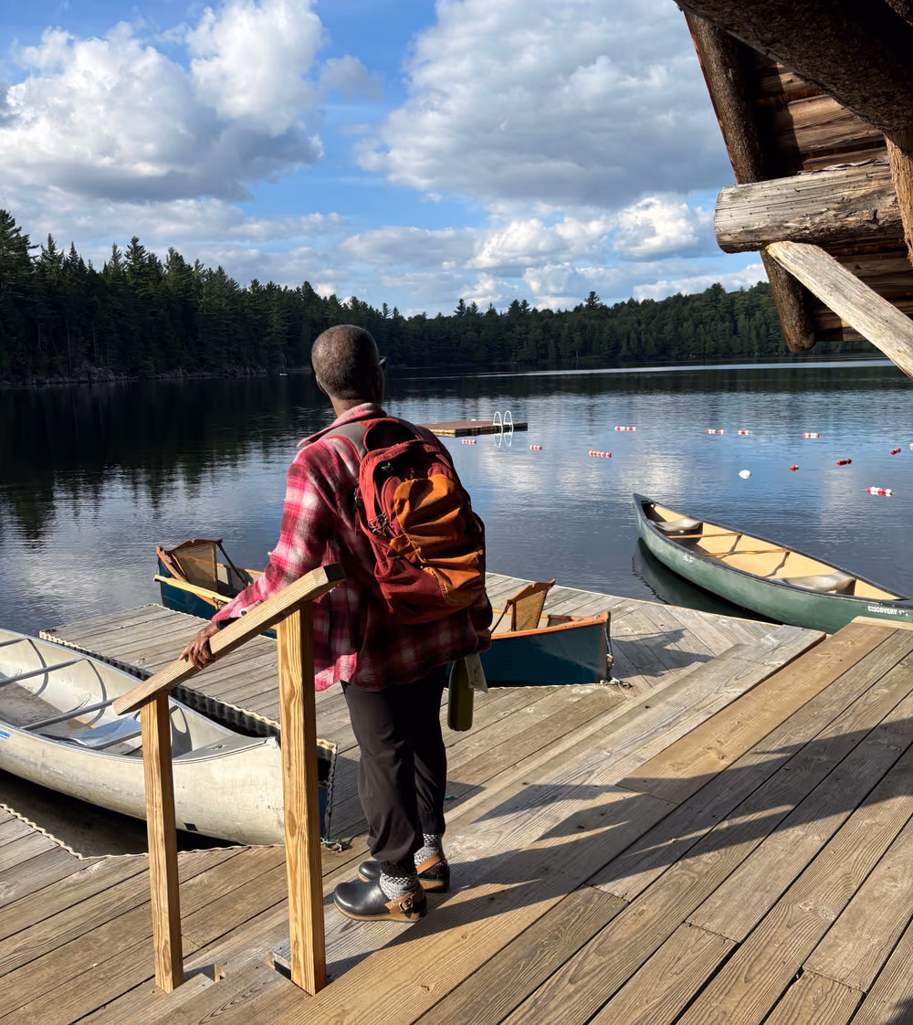 A participant stepping down the dock toward the canoes