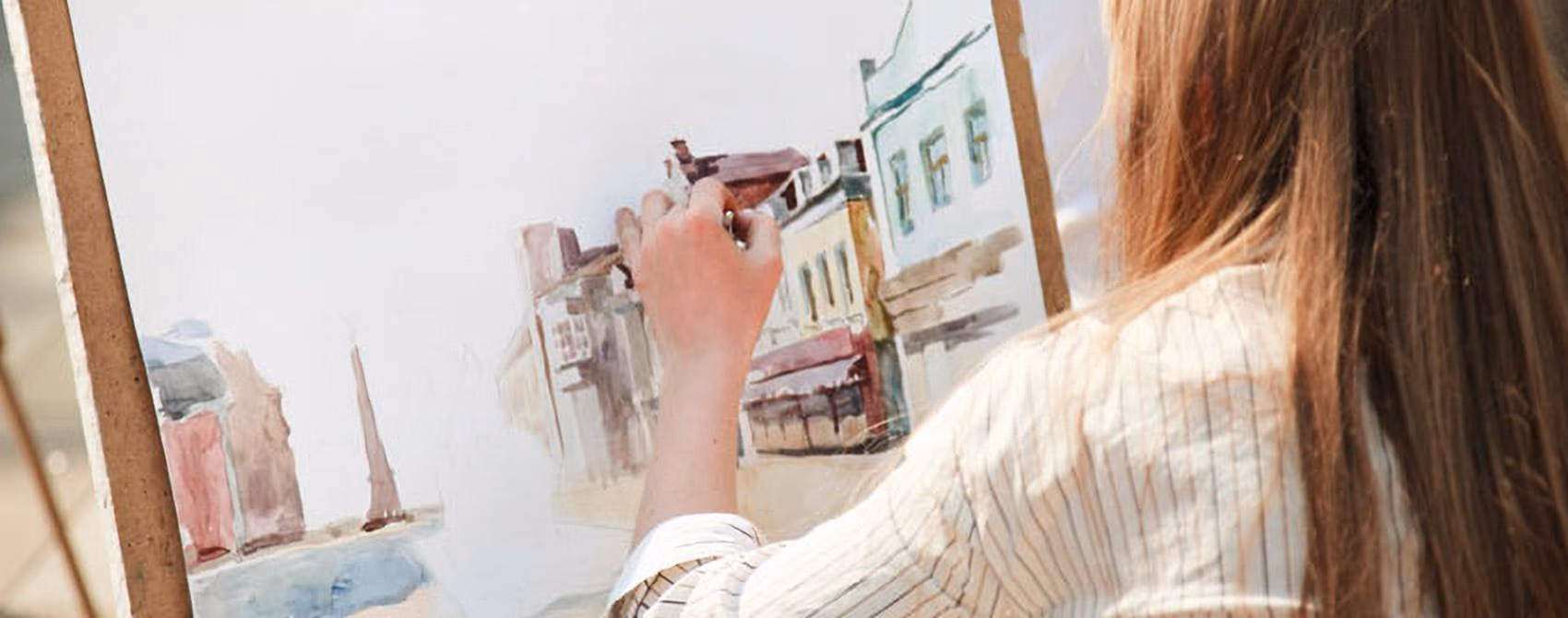 An artist painting a watercolor of the downtown storefronts