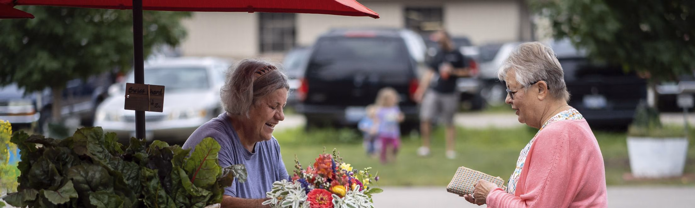 Shoppers and a vendor at a Saturday Farmers Market table