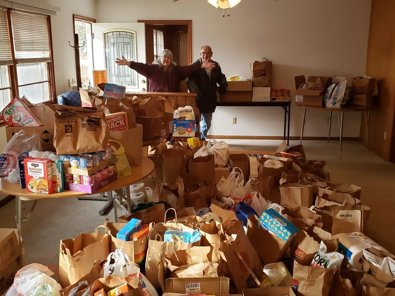 Volunteers at the Edgerton food pantry stand behind hundreds of bags of donated food.