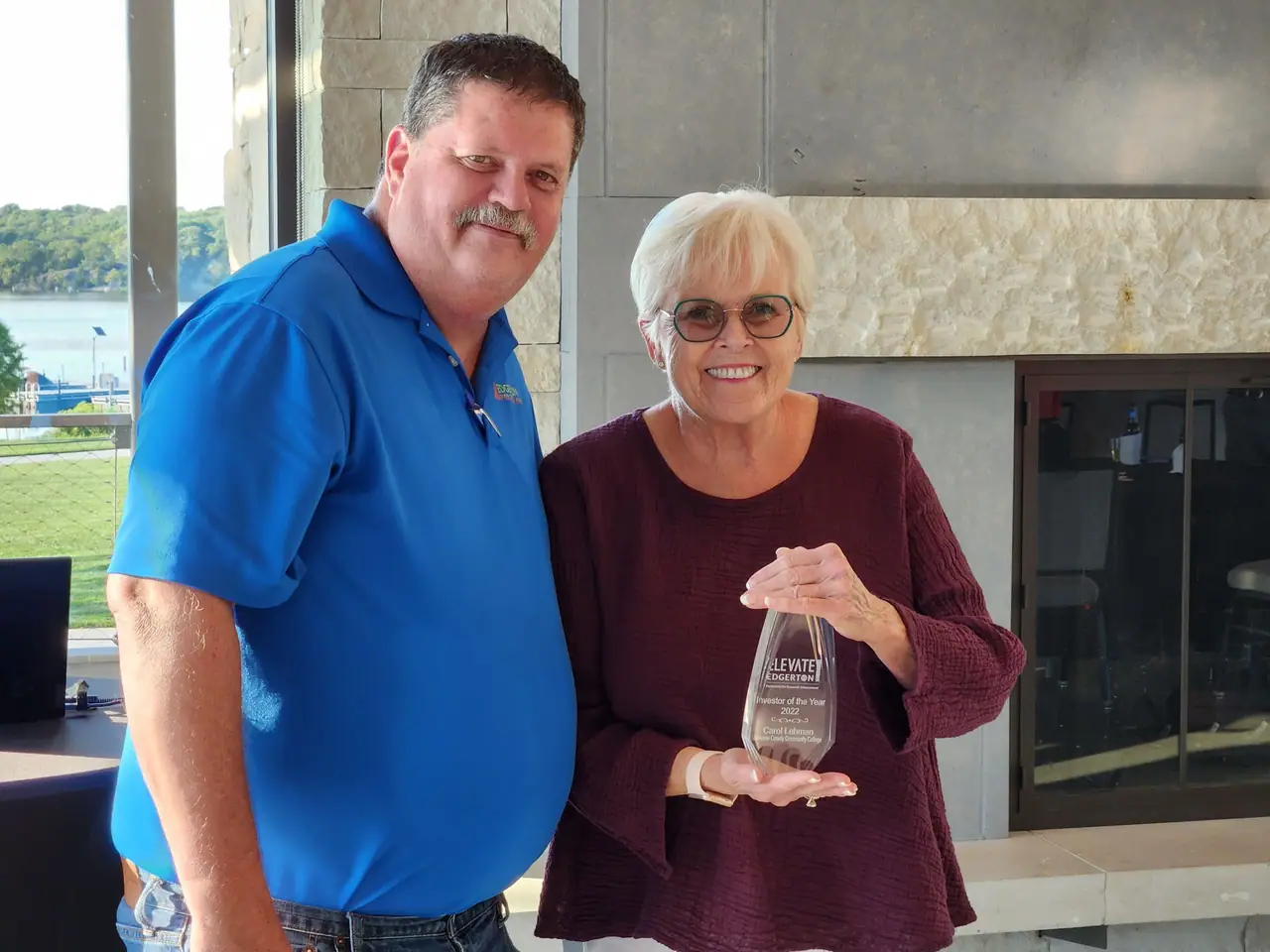 Mayor Donald Roberts and 2022 Investor of the Year Carol Lehman smiling, she holds her award.