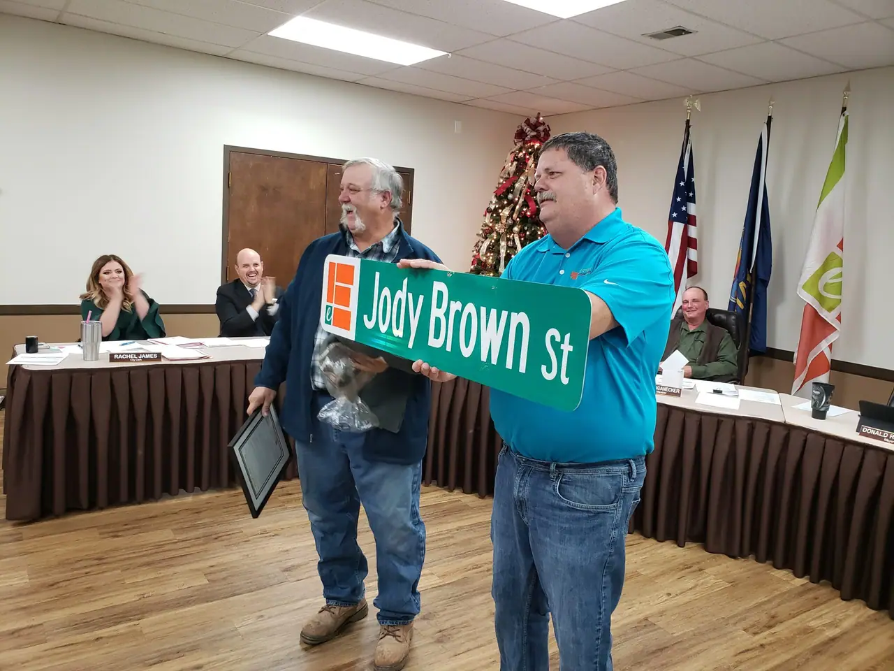Mayor Donald Roberts holds a street sign that reads Jody Brown St as Councilmember Brown smiles.