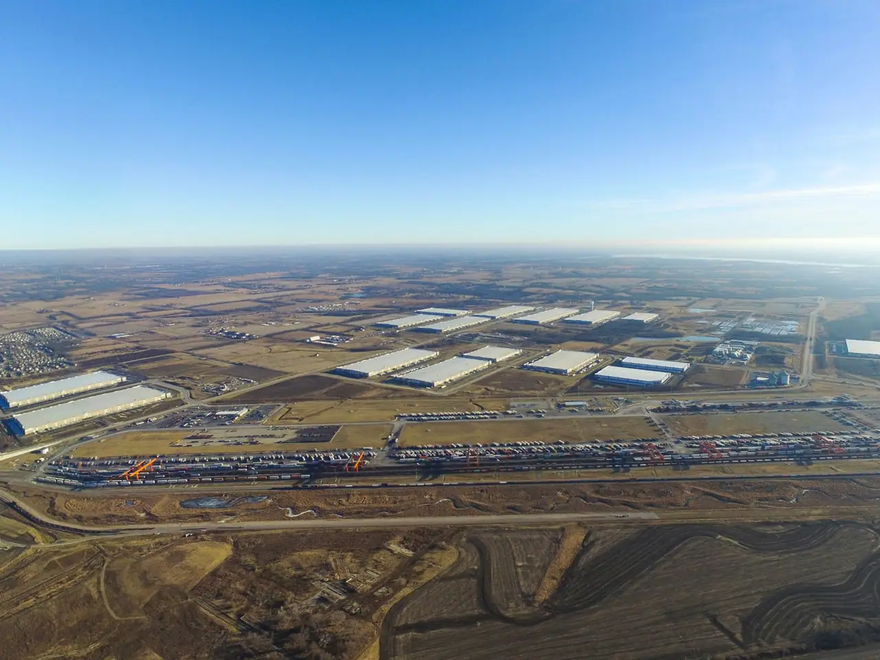 Logistics Park Kansas City from the air, with the intermodal yard, long warehouse roofs and open farmland beyond.