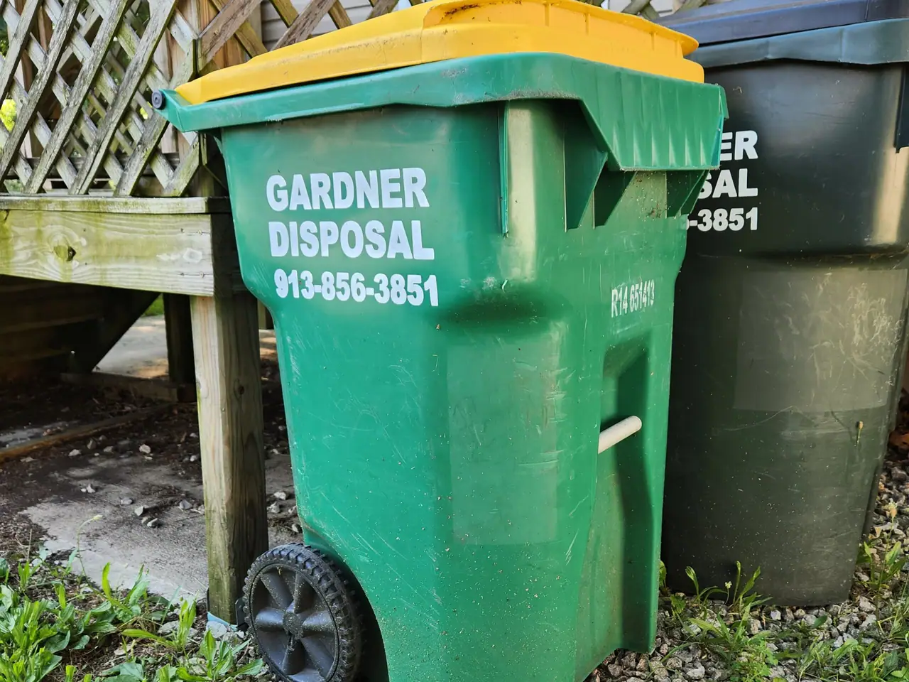 A green Gardner Disposal recycling cart outside a home in Edgerton.