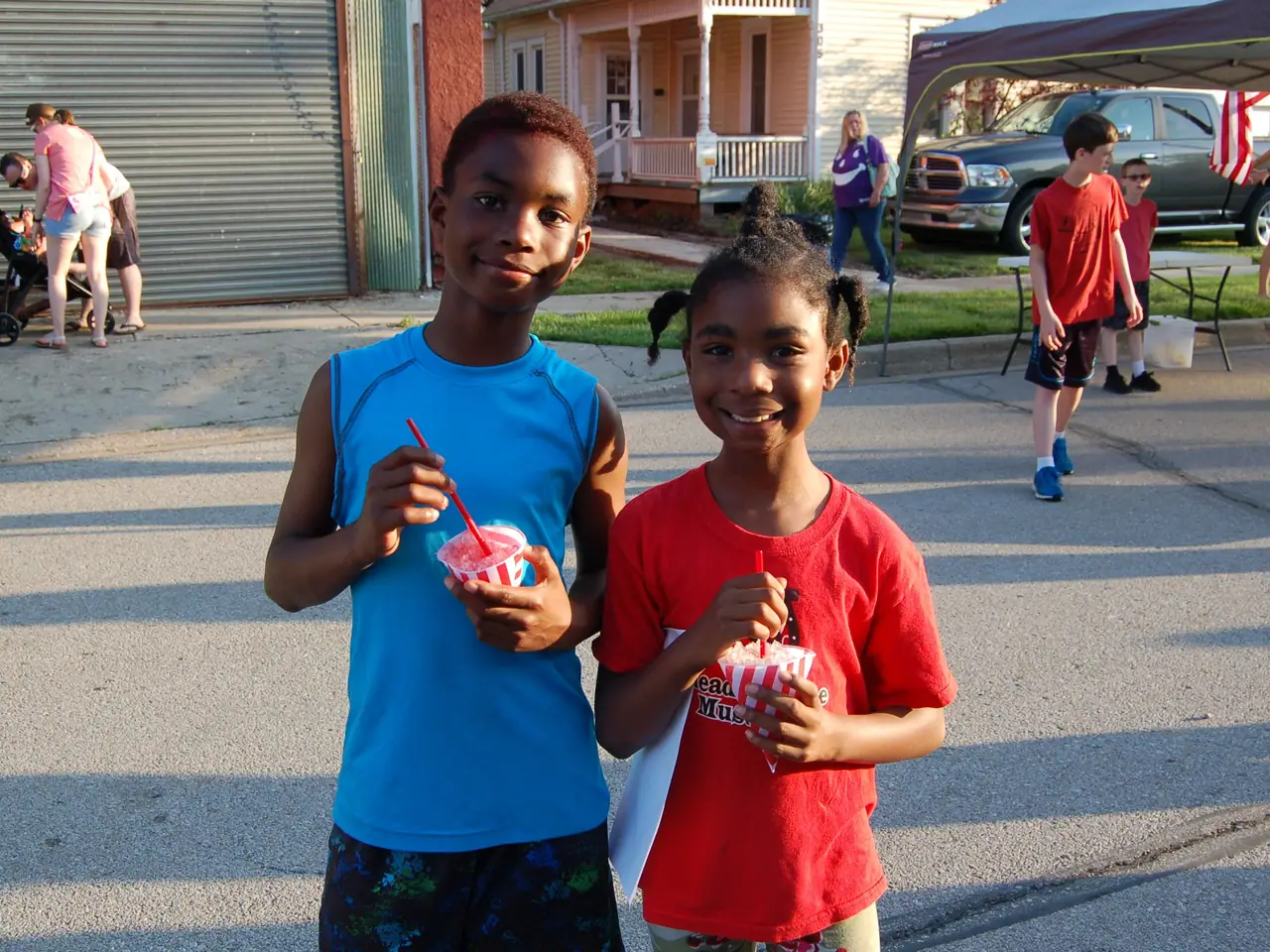A brother and sister pose with snow cones at the summer kickoff block party.