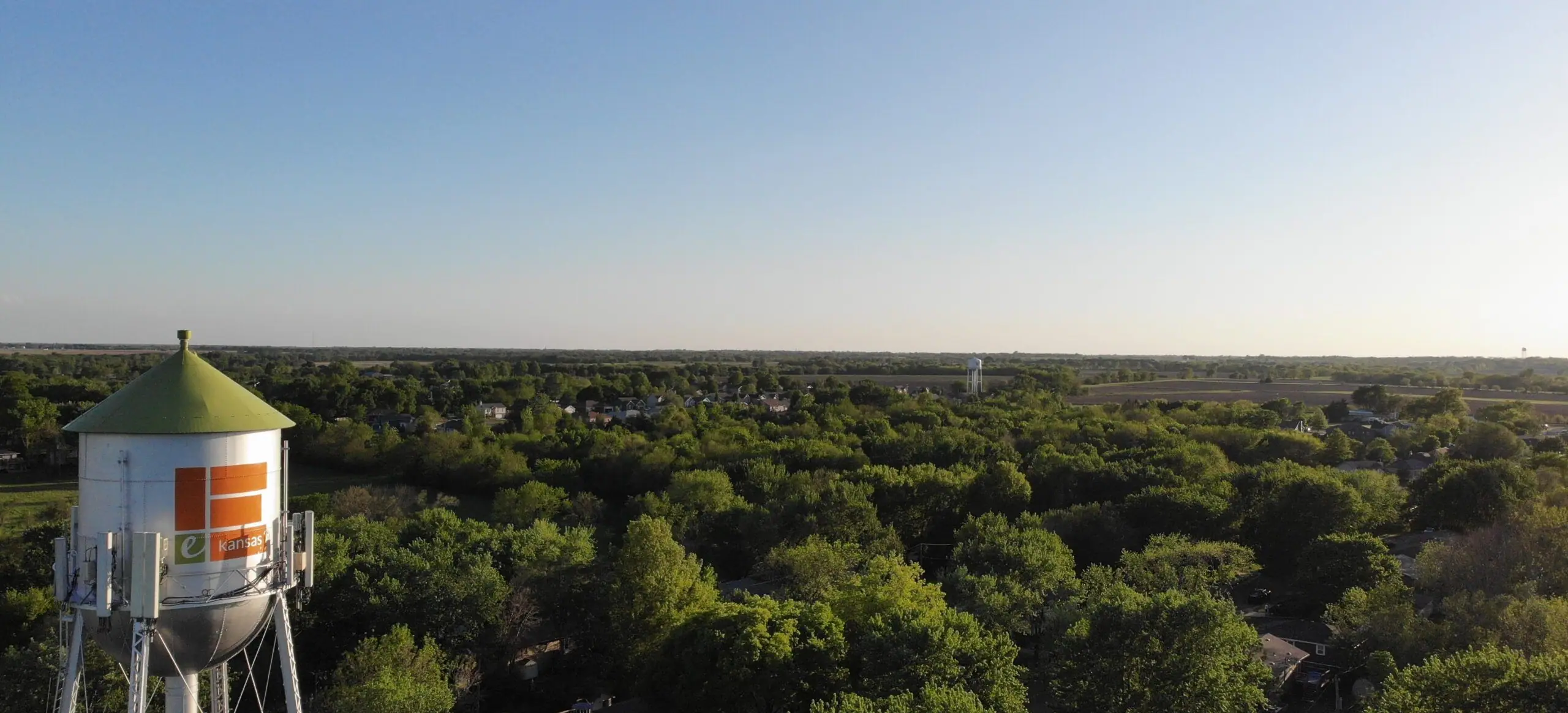 The Edgerton water tower rising above a green tree canopy under a clear blue sky.