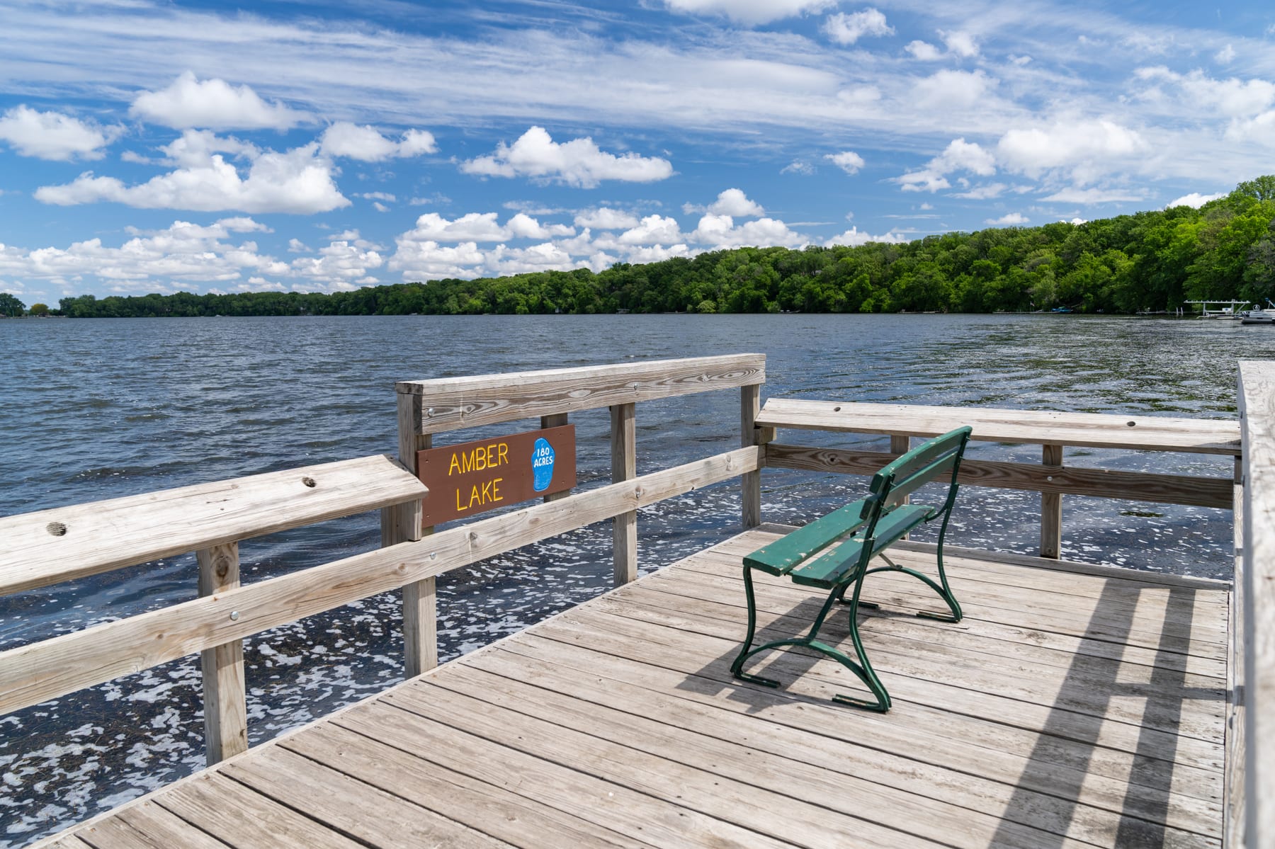 The Amber Lake pier and its painted lake sign, water reaching flat to the prairie horizon