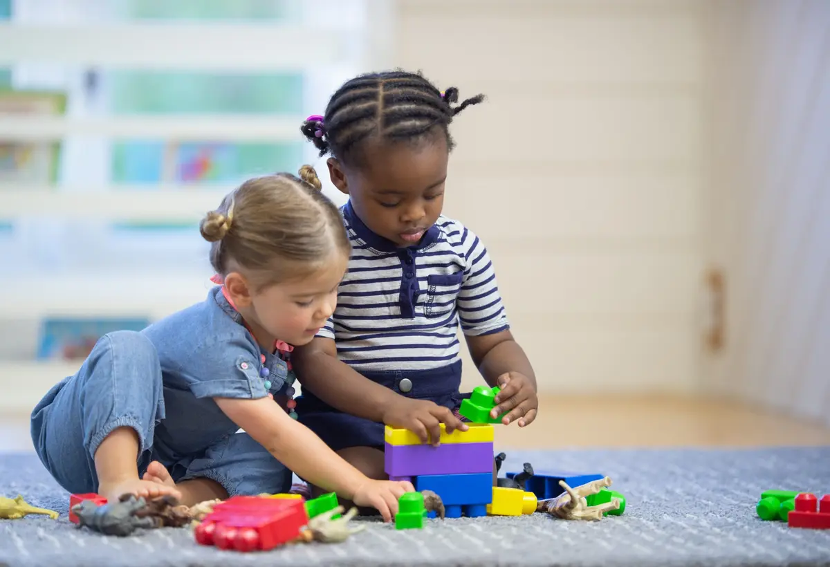 Two young children building a colorful tower together