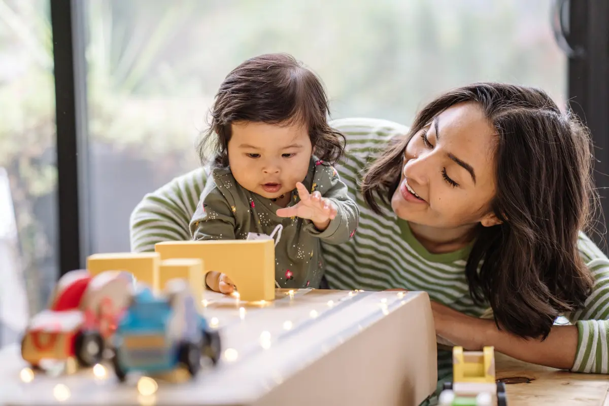 A caregiver and young child exploring toys together