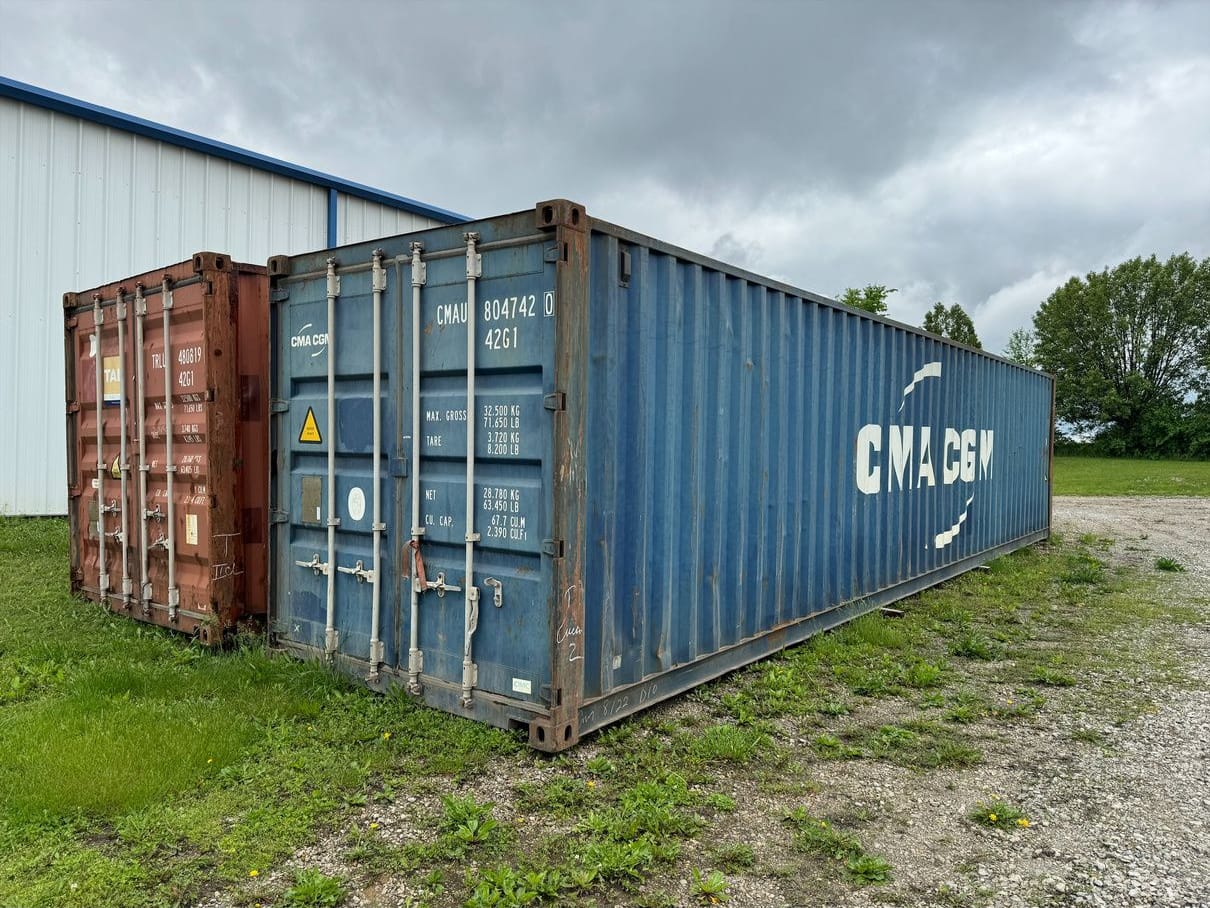 Two shipping containers set on gravel as collection pods for tires, electronics, and other items banned from landfills.