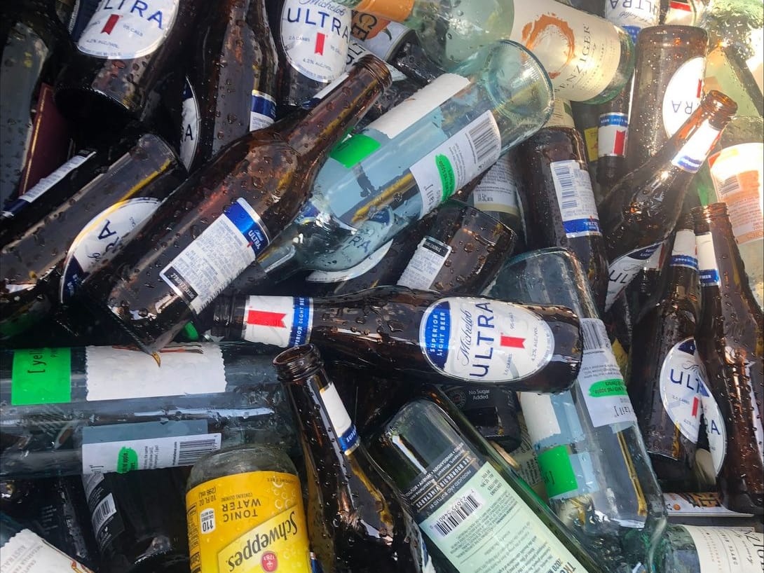A trailer bed heaped with glass bottles and jars collected for recycling.