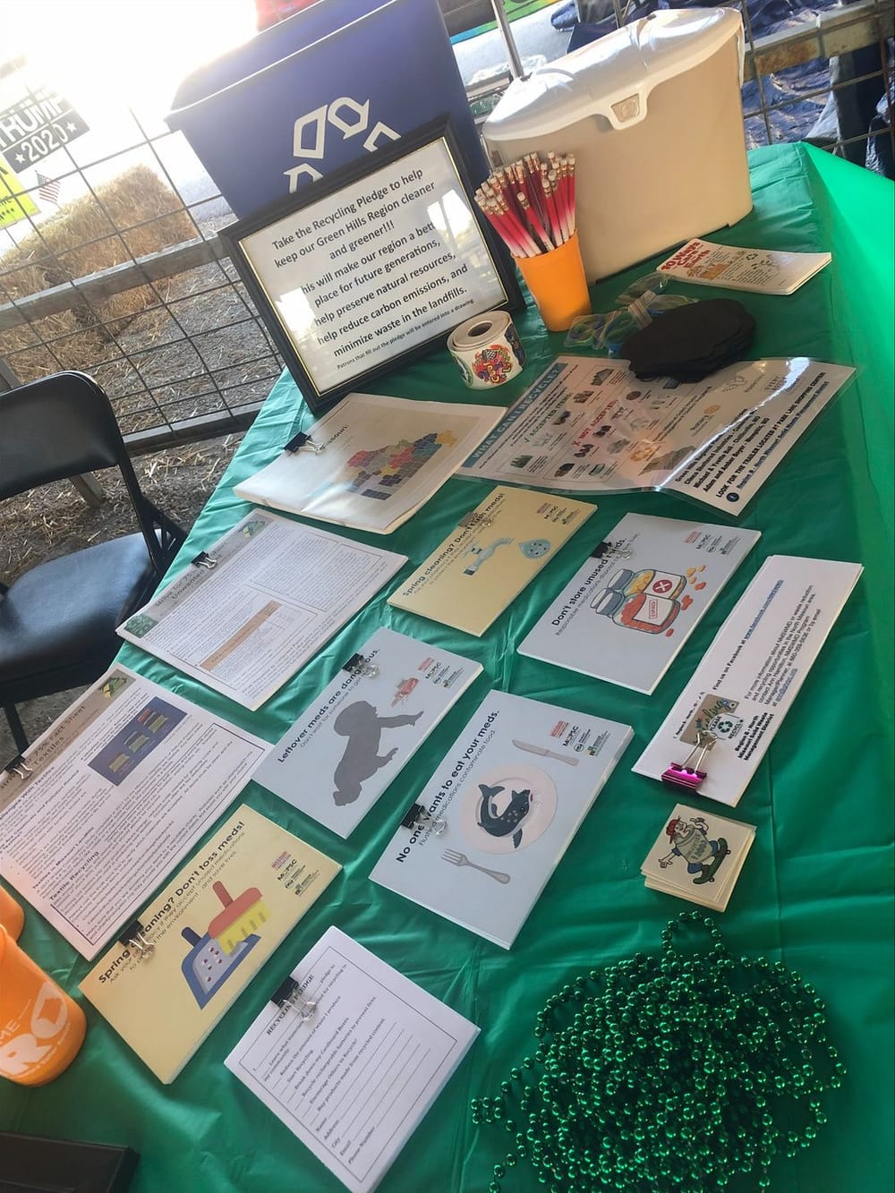 A green-covered table of recycling handouts and a pledge sign at the solid waste district's festival booth.