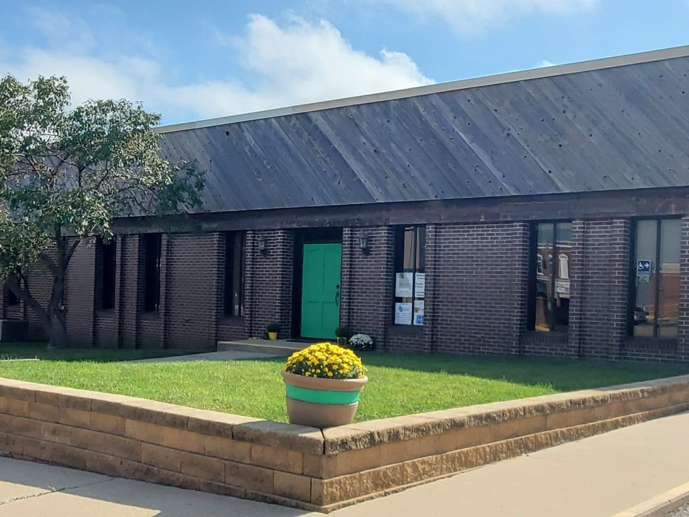 The Green Hills Regional Planning Commission office, a long low brick building with a green door and a planter of yellow mums out front.
