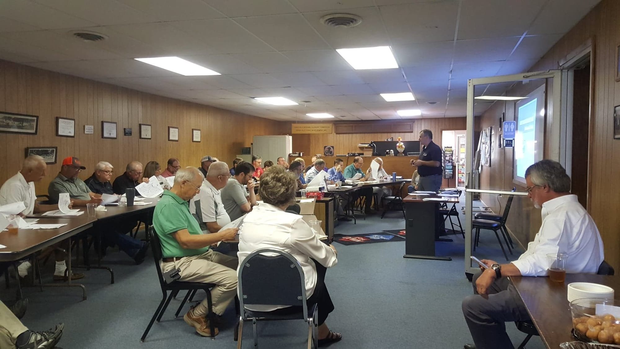 County commissioners and city representatives seated at long tables during a Transportation Advisory Committee meeting.