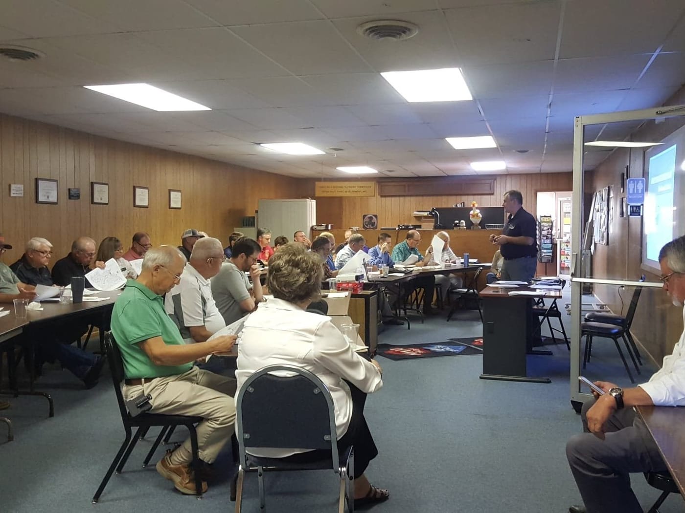 County commissioners and city representatives seated at long tables during a Transportation Advisory Committee meeting.