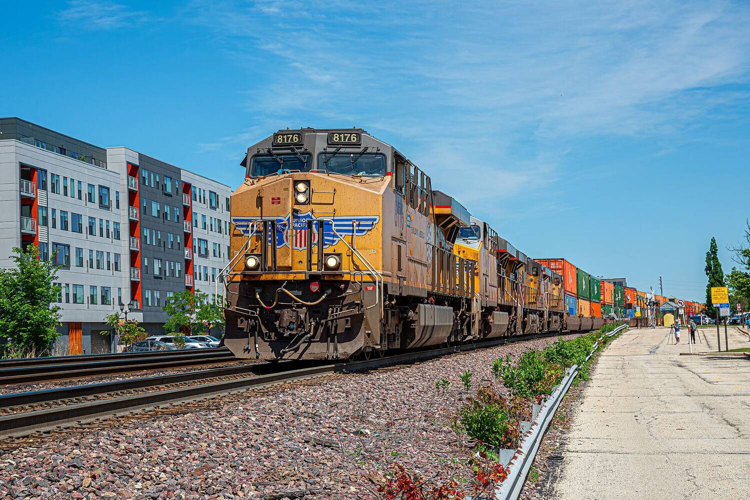 A yellow Union Pacific freight locomotive leading a train through a sunny Illinois town.