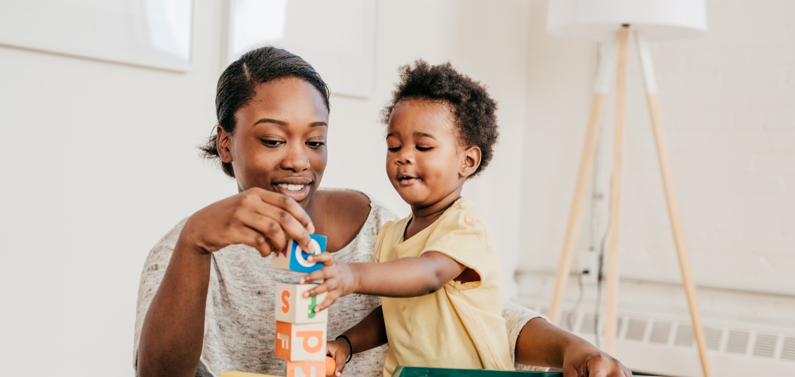 A woman and a toddler stacking wooden blocks together